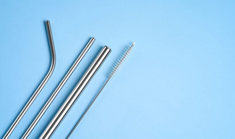 Metal drinking straw with cleaning brushes and tools used to remove bacteria and residue from inside the straw for hygiene.